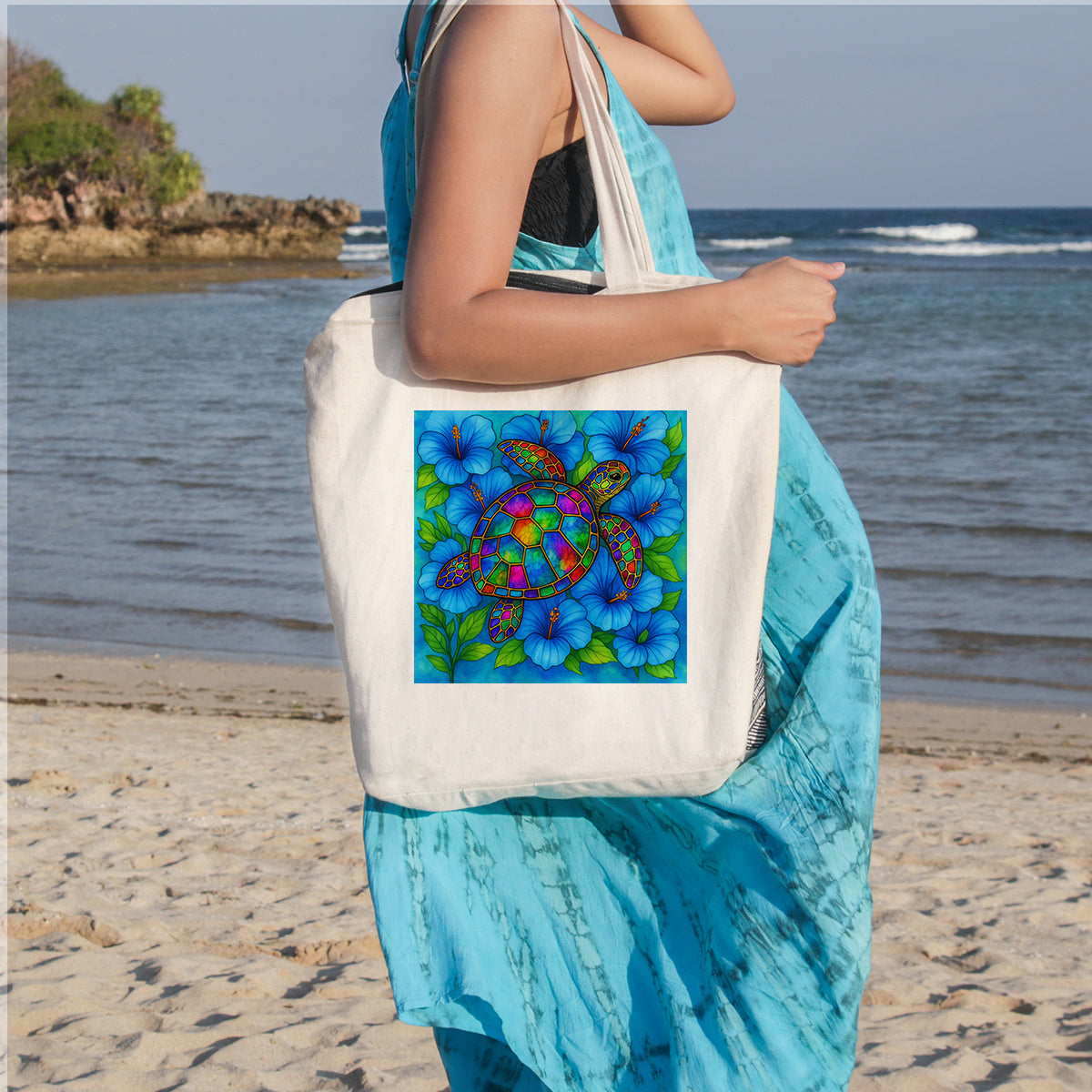Person holding a tote bag with a colorful turtle design on a beach